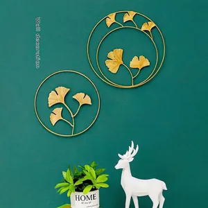 Golden ginkgo leaf wall decor with circular frames on a dark green background