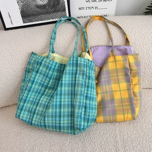 Detailed view of plaid canvas tote bags with colorful inner lining on a soft white sofa