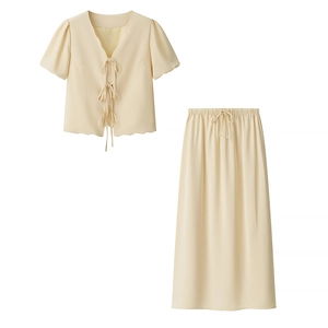Detail of beige two-piece set featuring bow tie-up top and elastic waist skirt