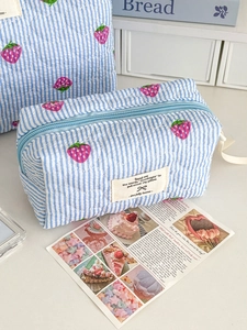 Quilted blue striped cosmetic bag with strawberry print and side handle for travel