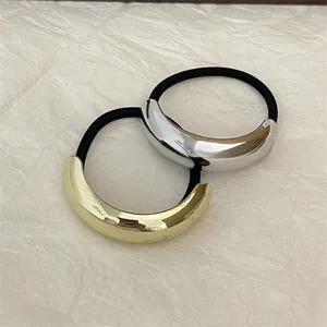 Close-up of sleek gold and silver metal crescent hair ties on soft textured paper