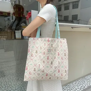 Close-up of floral tote bag with cute teddy bear patterns and light blue handles