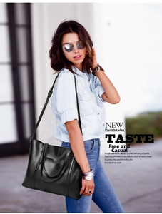 Detailed view of black leather tote bag with fine texture and adjustable strap on a model