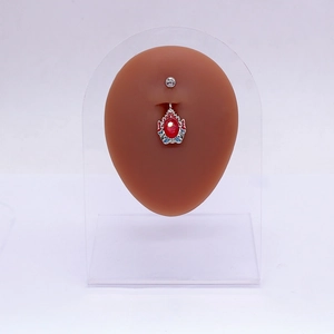 Piercing de nombril argenté avec gemme rouge et émail bleu sur modèle en silicone