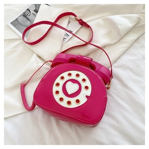 Detail of creative vintage phone-shaped crossbody bag in bright rose pink patent leather