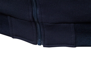 Detailed close-up of navy waffle knit fabric and ribbed hem on a men's stand collar jacket