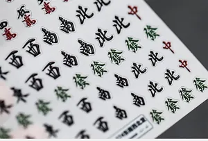 Vista macro dettagliata di adesivi per unghie 3D mahjong con caratteri rossi e verdi