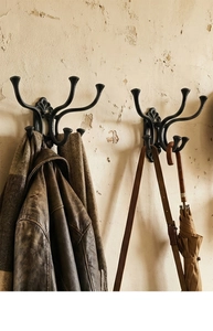 Macro shot of vintage cast iron antler wall hook holding heavy jackets and umbrella