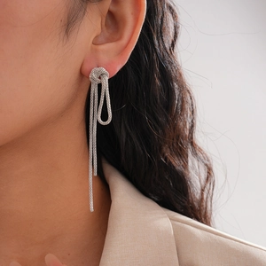 Detail of silver knotted tassel earrings with metallic mesh chains on a female model