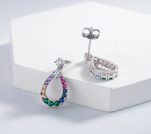 Macro shot of silver teardrop earrings with multi-colored crystals on white stone base