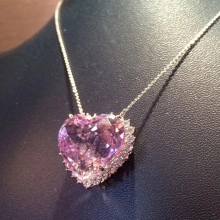 Macro detail of a large pink heart-shaped gemstone pendant with sparkling crystal halo