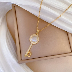 Detailed view of cat eye stone key necklace on beige jewelry box with silk background