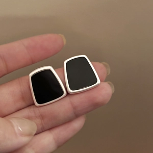 Detail of geometric trapezoid stud earrings with black resin and silver metal border