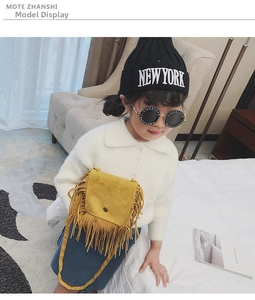 Close-up of yellow tassel crossbody bag worn by a child in a white sweater outfit