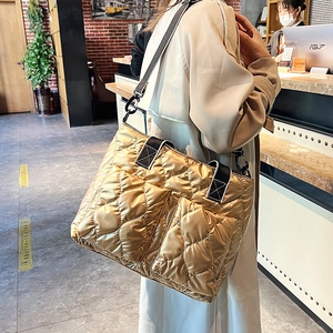 Detailed view of golden quilted tote bag with wide nylon strap and large pockets