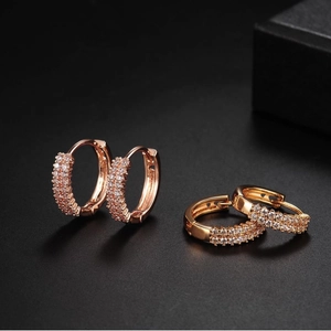 Sparkling double-row zircon hoop earrings in gold and rose gold on dark background