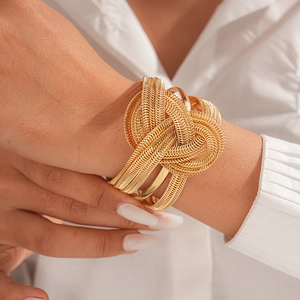 Close-up of golden multi-layer braided chain cuff bracelet with textured knot detail