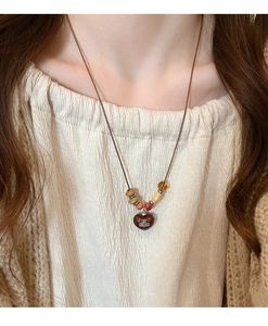 Detailed close-up of retro wooden beaded necklace with heart pendant and Saturn logo