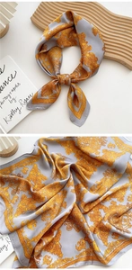 Detailed close-up of gray silk scarf featuring gold baroque print and smooth texture