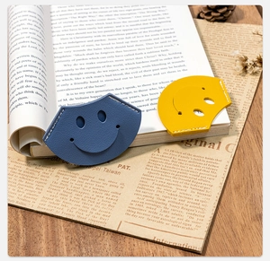 Detail view of smiley face PU leather bookmarks with stitching on vintage book background