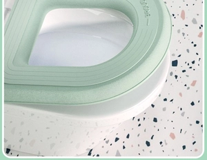 Close-up of light green waterproof EVA toilet seat cover with handle on a white toilet