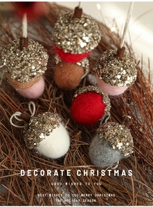 Close-up of wool felt acorn Christmas ornaments with gold sequins on pine needles