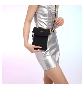 Detail of black quilted crossbody phone bag with adjustable cord on silver outfit