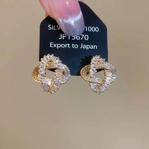 Macro shot of gold-plated hollow zircon earrings on a black presentation card