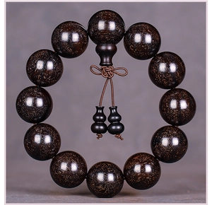 Macro detail of high-density sandalwood prayer beads with golden star textures and oil finish