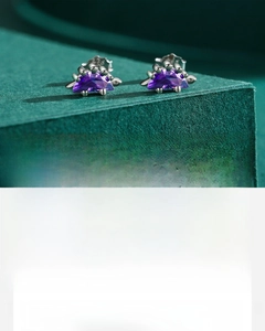 Detail of S925 sterling silver dinosaur earrings featuring hand-set purple zircon stones