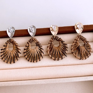 Détail de boucles d'oreilles gouttes en rotin tressé avec clous en zircon plaqué or