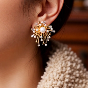 Macro shot of a 18k gold fireworks earring with pearls and sparkling zircon on woman ear