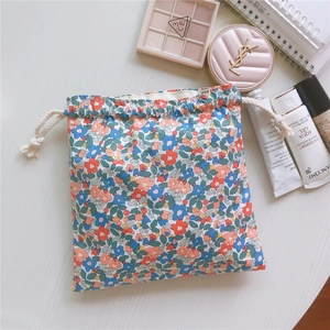 Floral cotton drawstring pouch with colorful small flower patterns on white wooden table