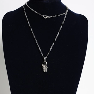 Close-up of astronaut pendant necklace with black visor on black display stand