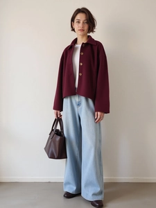 Detail view of burgundy single-breasted wool jacket with wide collar and brown handbag