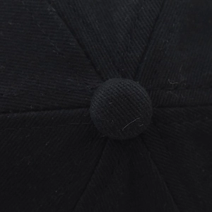 Close-up of the cotton twill crown and top button on a black baseball cap detail