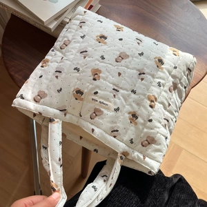 Detailed view of quilted cotton handbag with cartoon bear and floral pattern on wooden table