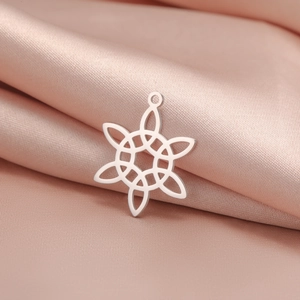 Macro d'un pendentif nœud celtique en acier inoxydable argenté sur tissu de soie rose
