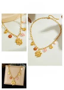 Macro details of gold charm necklace with sunflower, heart, and flower pendants