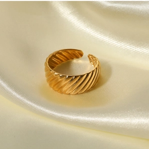 Close-up of golden adjustable twisted rope ring on elegant white silk background