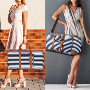 Blue striped canvas travel bag with leather trim shown carried by hand and on shoulder