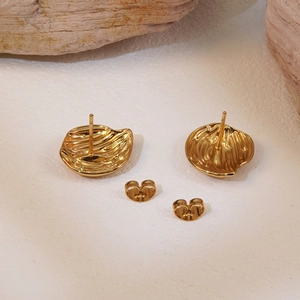 Minimalist gold titanium steel textured leaf stud earrings on a natural stone background