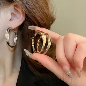 Large geometric hollow hoop earrings with irregular textured gold and silver finish