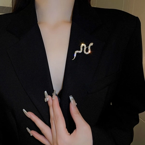 Detailed view of a gold-plated snake brooch with sparkling zircons on a black blazer