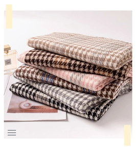 Close-up of stacked houndstooth scarves in beige, brown, pink, grey and black colors