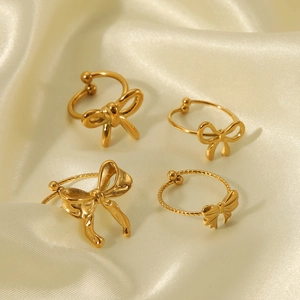 Elegant gold butterfly opening ring and earring set on minimalist cream silk fabric