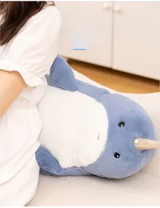 Blue and white plush narwhal cushion with gold horn used as a soft lumbar back support