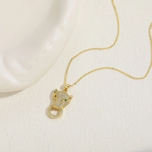 Detail of gold leopard pendant necklace featuring white cubic zirconia and emerald eyes