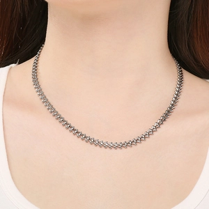 Detail of silver V-shaped woven chain necklace worn on neck highlighting the refined texture