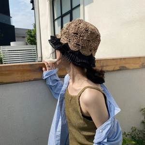 Detail of handmade straw hat featuring elegant black lace trim and hollow crochet patterns